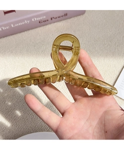 Close-up of a large amber translucent hair claw clip with a stylish twisted design