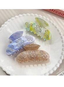 Detailed close-up of three elegant acetate hair claws with rhinestone floral accents