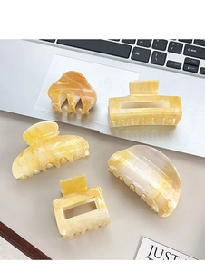 Détail de cinq pinces à cheveux jaunes marbrées, montrant la texture acrylique sur laptop