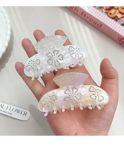 Detailed shot of resin claw clips with marble texture and rhinestone flower patterns