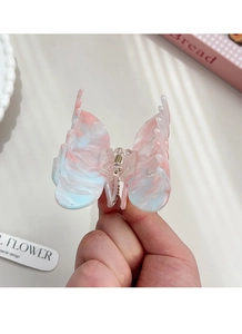 Detailed shot of a marble texture butterfly hair claw clip held in hand for scale