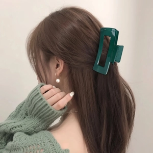 Minimalist dark green square hair claw clip and pearl earring on model from side view