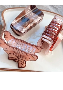 Détail de trois pinces à cheveux marrons avec relief de nœud sur une assiette blanche