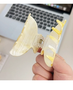 Vue détaillée d'une grande pince à cheveux papillon marbrée jaune avec ressort en métal