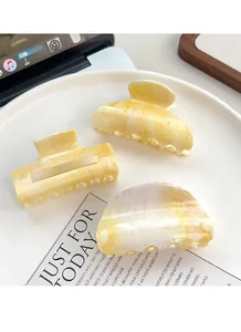 Lot de 3 pinces à cheveux à motif marbré jaune et blanc crème sur une assiette blanche