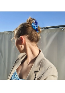 Blue bird shaped acetate hair claw clip worn on a bun for an elegant outdoor hairstyle
