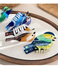 Detailed close-up of bird-shaped acetate hair claws showing pearlescent texture and colors