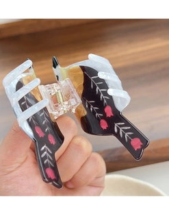 Detailed macro view of large acetate hair claw with pink tulip pattern and amber finish