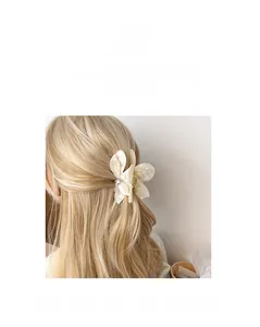 Detailed macro view of an elegant white floral hair claw clip with pearl-like texture and rhinestones