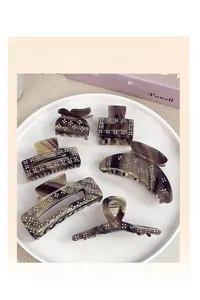 Brown acetate hair claws with marble texture and floral rhinestone details in white tray