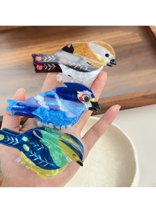 Detailed close-up of colorful acetate bird-shaped hair claws with glossy pearl finish