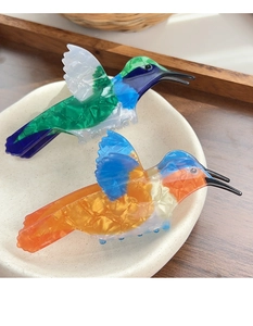 Artistic acetate hummingbird hair clips with colorful marble texture in a ceramic dish