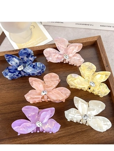 Close-up of six colorful flower-shaped acetate hair claws with marble texture and rhinestones