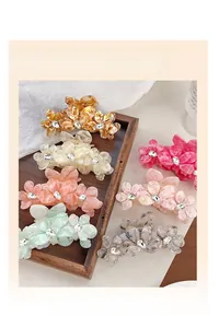 Gros plan de pinces à cheveux fleur en acétate marbré avec strass sur un plateau en bois