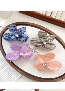 Detail of four flower hair claws with marble resin texture and center rhinestones