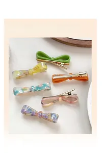 Détail de barrettes à nœuds colorées avec motifs marbrés et logo doré France Handmade