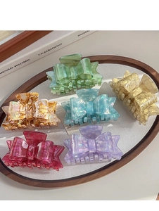 Selection of six colorful acetate bow hair claws with aurora texture in a decorative tray