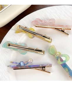 Dettaglio di fermagli per capelli in acetato con fiocco color pastello su piatto