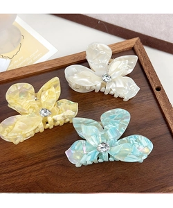 Detail of three butterfly hair claws in acetate with rhinestones on a wooden tray