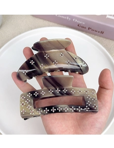 Detail of taupe marble acetate hair claws featuring delicate pink and white rhinestone flowers