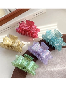 Detail view of five acetate bow hair claws in vibrant marble colors on a felt surface