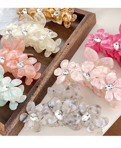 Détail de pinces à cheveux fleur en acétate coloré avec strass brillants au centre