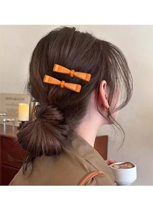Gros plan de pinces à cheveux orange en forme de nœud portées par un mannequin