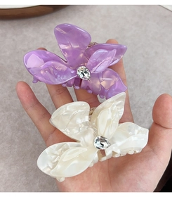 Detail of floral hair claws with pearlescent finish and drop-shaped crystal centers