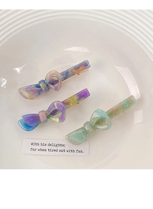 Dettaglio di fermagli per capelli in acetato colorato con texture marmorizzate e clip oro