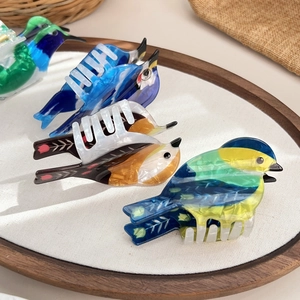 Chic bird shaped acetate hair claws with colorful marble patterns on a wooden tray