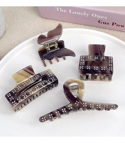 Detailed view of acetate hair claws with marble texture and delicate rhinestone flower clusters