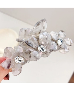 Détail de la pince à cheveux en acétate gris marbré avec design floral en cristal