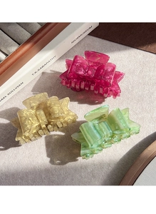 Detailed view of acetic acid bow hair claws in vibrant pink, amber, and light green shades