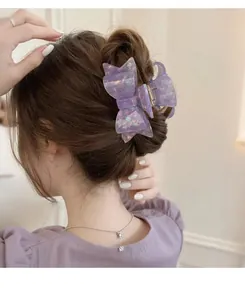 Detail of purple acetate bow hair claw clip with holographic glitter on a hair bun