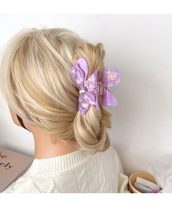 Close-up of a purple acetate flower hair claw clip with rhinestone on blonde hair