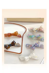 Macro detail of acetate bow hair clips with marble patterns in a stylish white tray