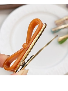 Vue détaillée d'une barrette à cheveux orange avec un clip en métal doré de type bec de canard