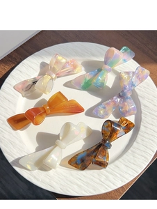 Detailed close-up of acetate bow hair clips with Barrette La France gold engraving