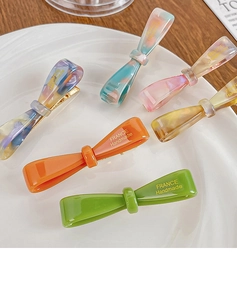 Détail de barrettes à cheveux en acétate coloré avec texture marbrée et logo doré