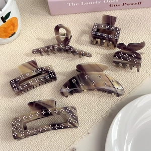 Elegant marble acetate hair claw clip set with floral rhinestone details on woven mat