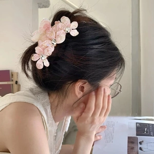Grande pince à cheveux fleurie en acétate avec strass portée sur un chignon