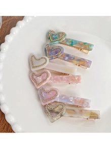 Détail de barrettes à cheveux coeur en acétate marbré avec strass sur plateau blanc