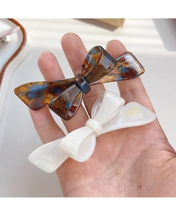 Macro detail of French bow hair clips in amber tortoiseshell and creamy white acetate