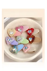 Detail of colorful heart-shaped hair clips with crystal accents on a white tray