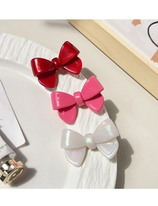 Détail de trois pinces à cheveux en forme de nœud en rouge rose et blanc perle brillant