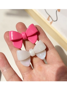 Détail de barrettes à cheveux nœud en acétate fuchsia et blanc nacré avec fini brillant