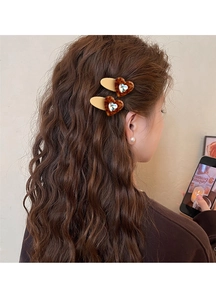 Detail view of heart-shaped leopard print hair clips with crystal inlay on brown curly hair