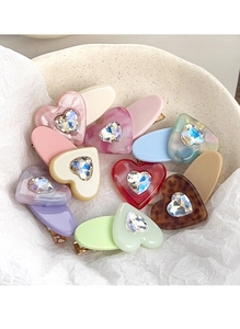 Macro view of assorted resin heart hair clips with rhinestones in a ceramic dish