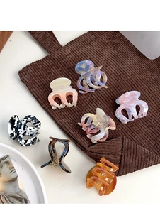 Detail view of acetate claw clips in marble patterns and various colors on soft fabric