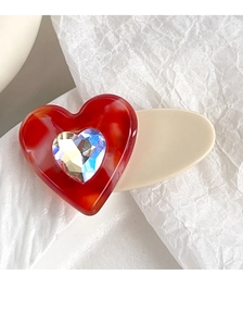Macro detail of heart hair clip featuring red marble texture and sparkling crystal inlay